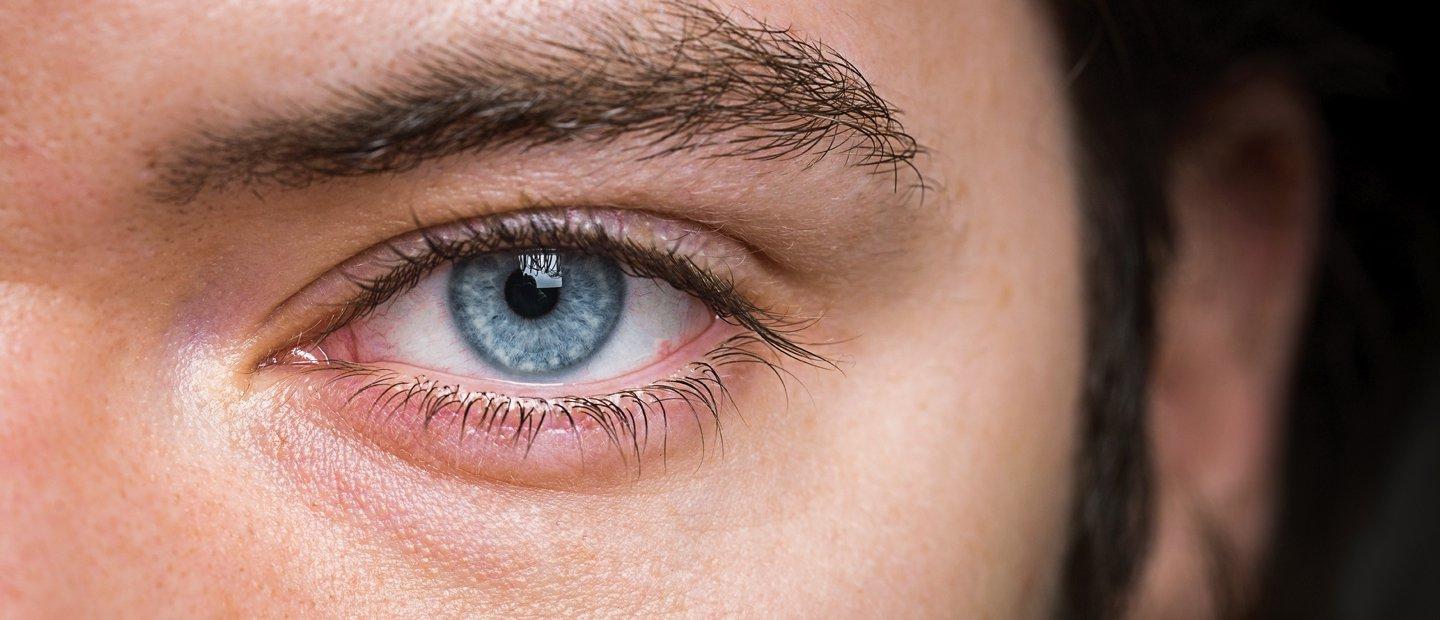 A very close up image of a blue eye with dark eye lashes.